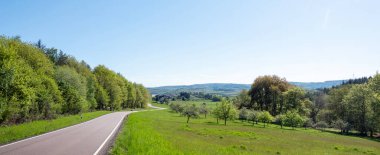 Alman doğa parkındaki ağaçların ve tarlaların taze bahar renkleriyle dolu kırsal alan mavi gökyüzünün altında saar-hunsrueck
