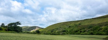 Corfe Kalesi yakınlarındaki tarlalar ve tepeler bulutlu gökyüzünün altında güney dorset kırsalında