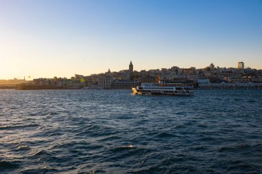 Galata Kulesi ve feribot gün batımında Boğaz 'da. İstanbul 'daki arka plan fotoğrafına git. İstanbul Türkiye - 9.7.2022