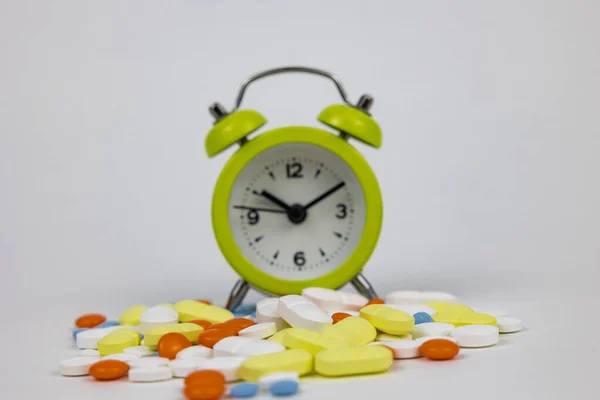 Taking pills or medicines on time concept photo. Medication adherence or routine background photo. Pills and clock. Selective focus on foreground.
