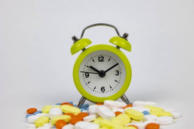 İlaç rutin konsept fotoğrafı. Haplarda bir saat ya da beyaz arka planda ilaçlar..