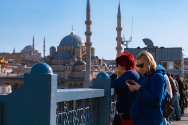 Turistler ve İstanbul. Arka planda Galata Köprüsü ve Yeni Cami 'deki veya Yeni Cami' deki turistler. İstanbul Türkiye - 9.24.2022