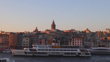 İstanbul manzaralı. Gün batımında feribot ve Galata Kulesi. Bosphorus Cruise konsepti 4K video. İstanbul Türkiye - 10.27.2022