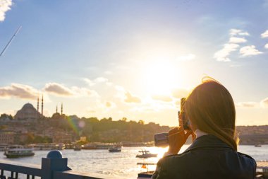 Günbatımında İstanbul 'un fotoğrafını çeken bir turist. İstanbul 'daki arka plan fotoğrafına git. Galata Köprüsü 'nden cep telefonuyla cami fotoğrafı çeken bir turist kadın..