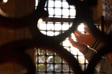 Islamic photo. Muslim man praying in the mosque behind the fences. Selective focus on the hands. Ramadan or kandil or laylat al-qadr or islamic concept photo. clipart