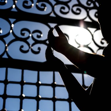 Kare biçiminde İslami konsept fotoğraf. Dua ederken Müslüman bir adamın silueti. Ramazan veya İslami arkaplan fotoğrafı.