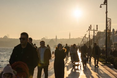 İnsanlar gün batımında Galataport rıhtımında yürüyor. İstanbul 'daki arka plan fotoğrafına git. İstanbul Türkiye - 12.24.2022