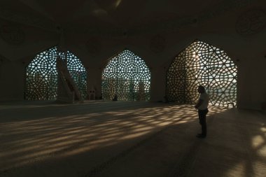 Muslim man praying or salah in a mosque. Islamic background photo. Shadows of geometric shapes on the ground. Marmara ilahiyat Mosque in Istanbul. Istanbul Turkiye - 9.26.2022