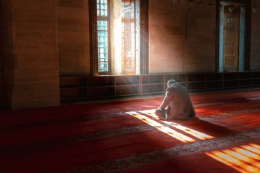İslami fotoğraf. Camide namaz kılan Müslüman bir adam. Pencereden güneş ışığı ve sis geliyor. Metinler için kopya alanı olan Ramazan veya İslami konsept fotoğraf.