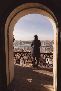 Galata Kulesi 'nin balkonundaki İstanbul' a bakan kadın. İstanbul Türkiye - 1.18.2023