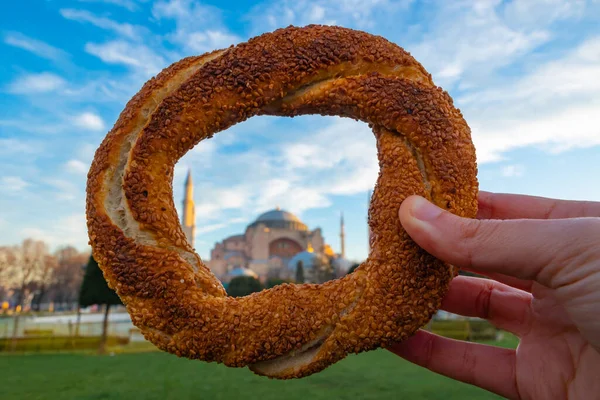 stock image Simit or Turkish Bagel with Hagia Sophia. Travel to Istanbul concept photo. Selective focus on the foreground.