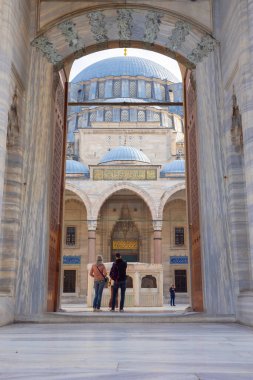 Avludan Süleyman Camii 'ne bakan turist çift. İstanbul 'daki arka plan dikey fotoğrafına git. İstanbul Türkiye - 12.23.2022