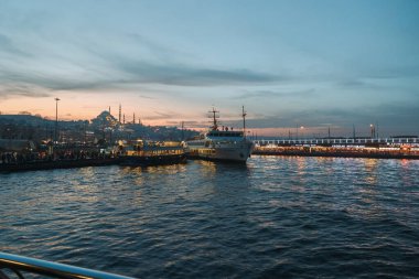 İstanbul manzarası gün batımında. Eminonu ufuk çizgisi olan Galata Köprüsü ve feribot. İstanbul Türkiye - 12.24.2022
