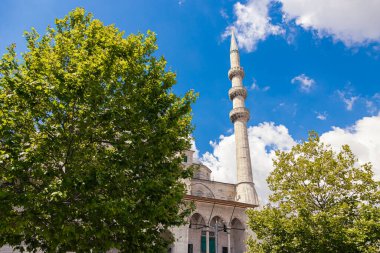 Eminonu Yeni Camii 'nin minaresi ya da ağaçlı Yeni Cami ve parçalı bulutlu gökyüzü. Ramazan veya İslami arkaplan fotoğrafı.