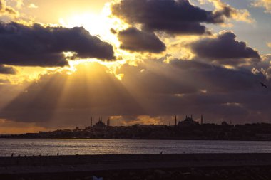 Günbatımında dramatik bulutlar ve güneş ışığıyla İstanbul silueti. İstanbul 'un Kadıköy' deki feribottan manzarası.