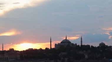 Ayasofya ve Sultanahmet ya da Mavi Cami manzaralı bir feribot günbatımında 4K görüntüsü. Ramazan veya İslami konsept video. İstanbul 'u ziyaret et.