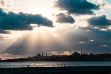 İstanbul 'un silueti, bulutlar ve dramatik gökyüzü arasında güneş ışığı. İstanbul 'u, Ramazan' ı veya İslami konsept arkaplan fotoğrafını ziyaret edin.