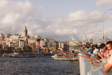 İstanbul manzaralı. Galata Köprüsü 'ndeki balıkçılar ve arka plandaki Galata Kulesi. İstanbul Türkiye - 9.10.2023
