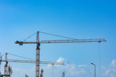 İnşaat alanı ya da inşaat endüstrisi konsepti. Mavi gökyüzü arka planına sahip iki vinç var..