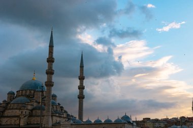 İslami fotoğraf. Eminonu Yeni Camii ya da Yeni Cami 'de gün batımında dramatik bulutlar. Ramazan Kareem veya bayram mübareği veya laylat al-qadr veya kadir gecesi arkaplan fotoğrafı.