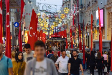 Nostaljik tramvaylı Türk bayrakları ve Istiklal Caddesi 'ndeki insanlar. İstanbul Türkiye - 10.28.2023