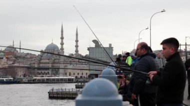 Arka planda Galata Köprüsü ve Yeni Cami 'deki ya da Yeni Cami' deki balıkçılar. İstanbul arka plan videosu. İstanbul Türkiye - 3.31.2023