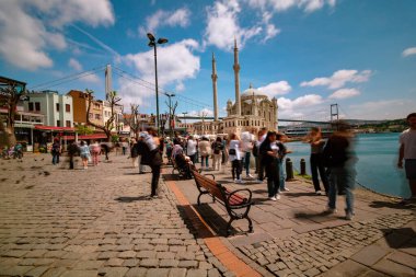 Ortakoy Camii ve turistler. İstanbul konsept fotoğrafını ziyaret edin. İstanbul Türkiye - 4.27.2024