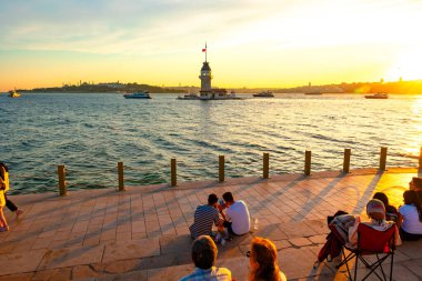 Kiz Kulesi, namı diğer Maiden 's Tower gün batımında ve insanlar etrafı geziyor. İstanbul Türkiye - 6.8.2024