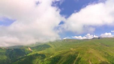 Gündüz vakti yeşil tepelerde hareket eden bulutlar. Doğa zaman arkaplanı 4k video.