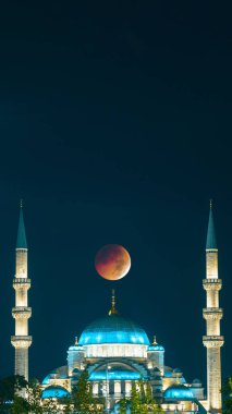 Mosque and eclipsed moon. Ramadan or eid al-adha or eid al-fitr or kadir gecesi or laylat al-qadr concept vertical photo. clipart