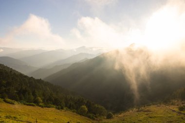 Sis ve sisli dağ sırasının gün batımı manzarası. Manzara arkaplan fotoğrafı.