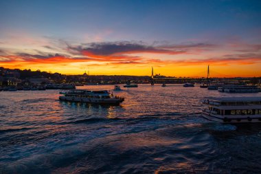 İstanbul 'un gün batımında feribot ve dramatik bulutlarla çevrili Altın Boynuz ve şehir manzarası. İstanbul Türkiye - 10.14.2024