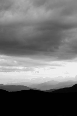 Katmanlı dağlar ve bulutlu gökyüzü. Siyah beyaz manzara dikey fotoğraf.