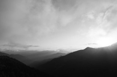 Gün batımında sisli dağ sıraları. Siyah beyaz manzara fotoğrafı..