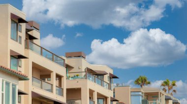 Panorama Beyaz Kabarık Bulutlar La Jolla, California 'da cam parmaklıklı konut binaları. Açık gri gökyüzüne karşı farklı tasarımları olan mahalle binalarının dışında..