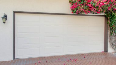 La Jolla, California 'da yanında bougainvillea olan Panorama Garajı. Garajda gri çerçeveli beyaz bir bölüm kapısı ve kırmızı tuğlalı bir lamba var..