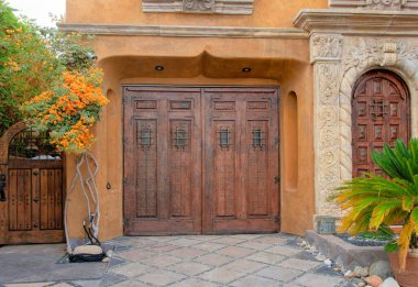 Panorama Sun, La Jolla, Kaliforniya 'daki eski Akdeniz tarzı evi aydınlattı. Soldaki kapının yanında büyük, koyu ahşap bir çift kapı ve sağdaki kemerli ön kapı antika çerçeveli..