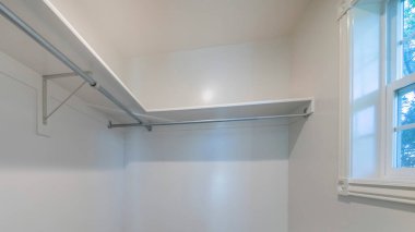 Panorama Küçük, içi beyaz ve pencereli dolapta boş bir yürüyüş. Duvarlarda halı döşeme ve raflar var. Ön ve sağ duvarlarında metal frenler ve çubuklar var..