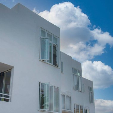 Kaliforniya, La Jolla 'daki modern beyaz konut binası. Önünde muz ağaçları, sağında cam ve balkon olan yan pencereli bir binanın manzarası..