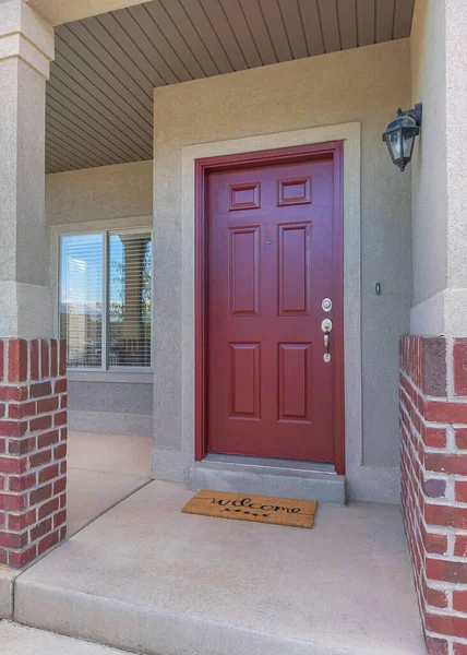 Stock image Vertical Red front door of a house with red bricks siding and railings at the porch. Front porch of a house with a view of the neighbor's house garage on the left.