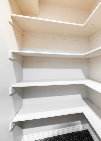 stock image Vertical White linen closet with wall mounted shelves and carpeted floor. Narrow walk-in closet with built-in shelves on the front and right walls.