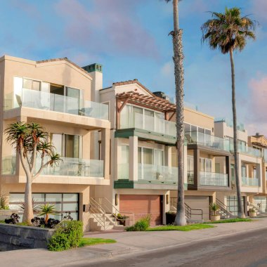 Günbatımında Kare Kabarık Bulutlar. La Jolla, California 'da çok katlı evler. Balkonlarda cam korkuluklu evler ve yol kenarında sütun palmiye ağaçları..