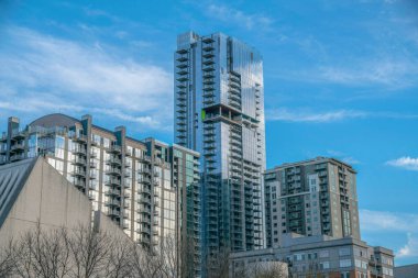 Austin Texas apartmanları ya da binalar bulutlu mavi gökyüzüne karşı yükseliyor. Modern mimari tasarımlı yapıların yer aldığı gökdelen manzarası.