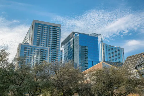 Austin Texas 'ta apartmanları ve ofis binaları olan gayrimenkuller. Mavi gökyüzü, bulutlar, arka plan ve ağaçlarla dolu şehir silüeti..