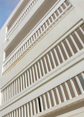 Günbatımında dikey kabarık bulutlar La Jolla, California 'daki beyaz bir binanın alçak açılı görüntüsü. Açık gri metal parmaklıkları ve terası gökyüzünün arka planında olan bir binanın dışı..