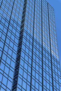 Camdan pencereleri olan gökdelen açık mavi gökyüzünü yansıtıyor. Gündüz vakti Austin Texas şehir merkezindeki modern iş binasının dış görünüşü.