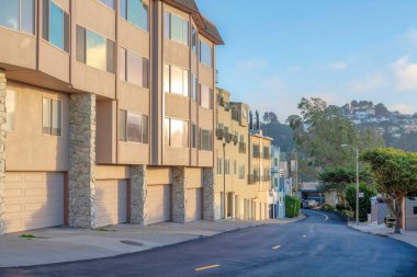 Yol kenarındaki garajı ve arkası dağ manzaralı apartmanlar. San Francisco, asfalt yolu ve sokak lambaları olan CA mahallesi..