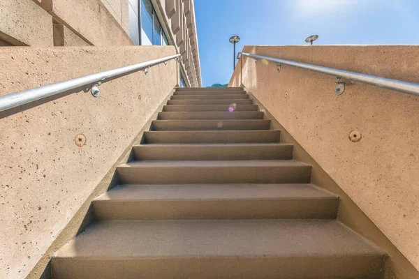 stock image View from the bottom of staircase outside a building with blue sky and sunlight. Outdoor stairway with concrete steps and metal railings in downtown Austin Texas.