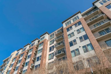 Austin, Teksas, orta katlı bir apartmanın alçak açılı görüntüsü. Balkonları ve resim pencereleri olan bir apartman binası cephesi.