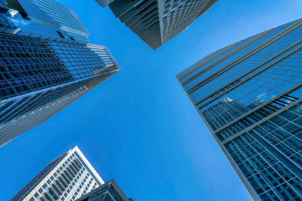Low angle view of corporate and residential skyscrapers in Austin, Texas. Four high-rise buildings with reflective glass exterior against the blue sky background.